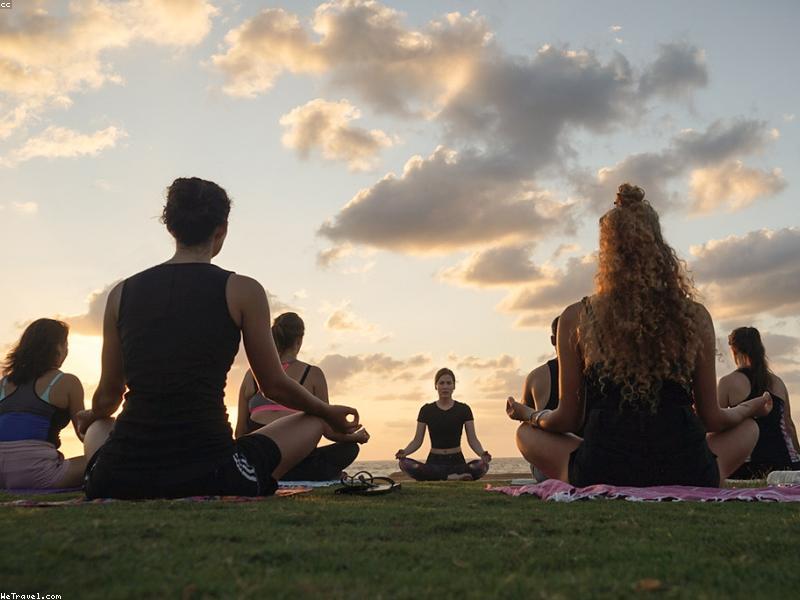 Group of people practicing yoga on a grassy lawn at sunrise