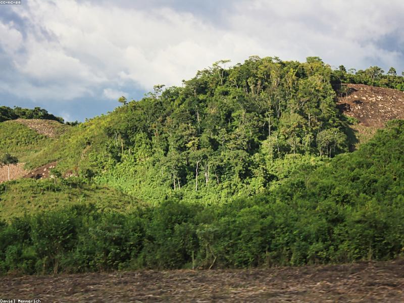 A scenic view of a mountain path with a backpack resting on a rock