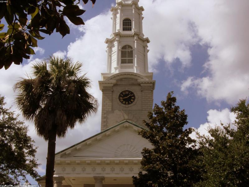 Couple walking hand in hand in Savannah's Historic District with oak trees