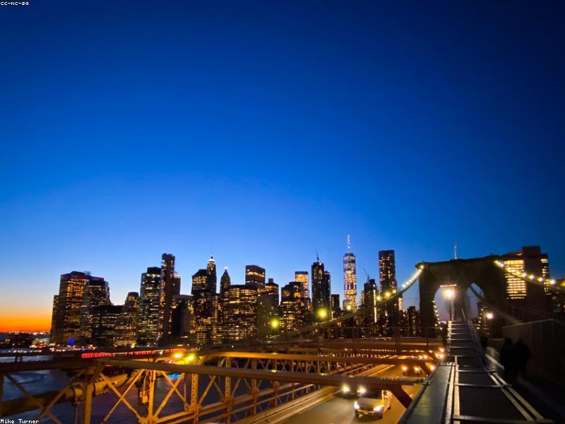 Couple walking on Brooklyn Bridge with city skyline in background